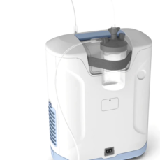 Inogen At Home oxygen concentrator with humidifier bottle and tubing attached, showing the side air vents and rear power inlet