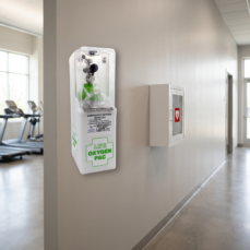 LIFE OxygenPac emergency oxygen unit wall-mounted beside an AED cabinet in a fitness club hallway