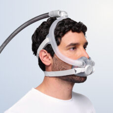 Hombre con la máscara facial completa AirTouch F30i Clear, vista de perfil, con la manguera conectada arriba de la cabeza