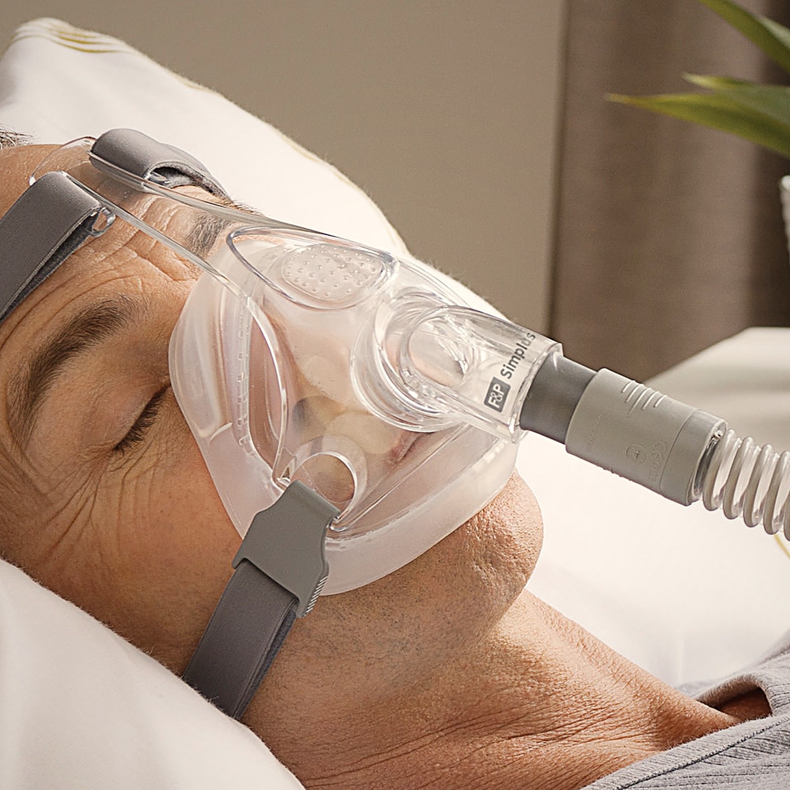 Hombre durmiendo con la máscara CPAP facial completa Simplus de Fisher & Paykel